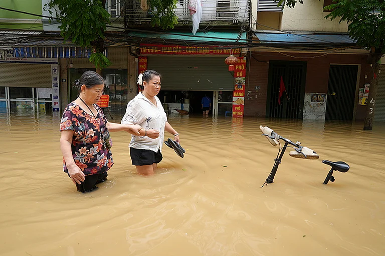 People wade in a flooded street in Hanoi - | Photo: AP/Hau Dinh